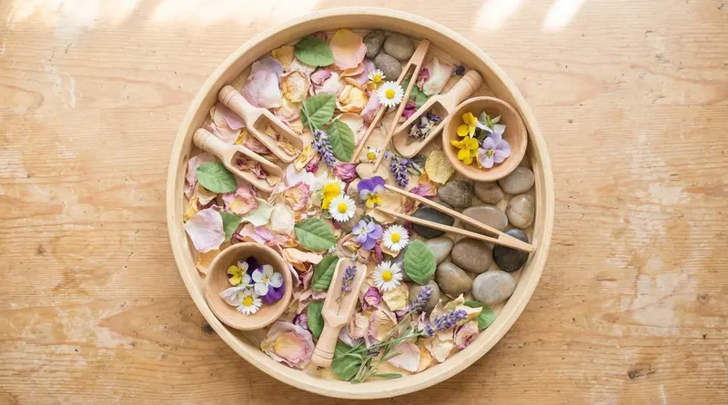 Spring Montessori sensory bin with flower petals, leaves and wooden scoops
